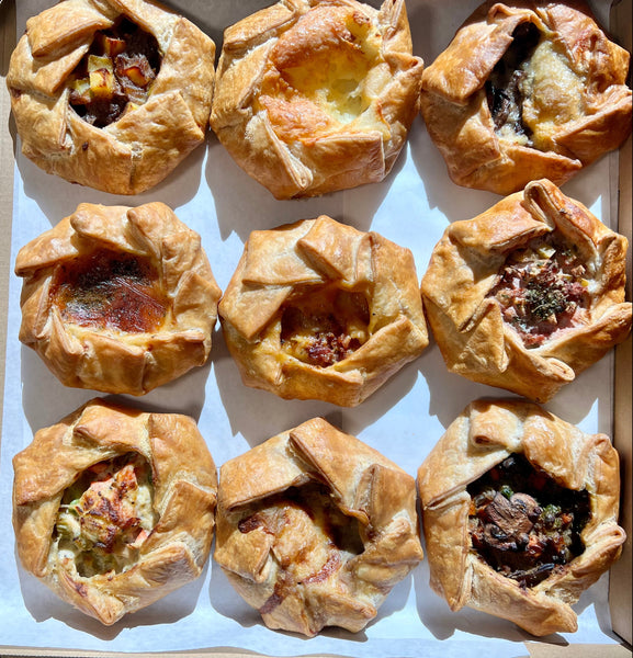 Box of pastry appetizers with various fillings on a wooden surface